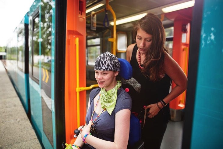 Auf dem 2. Bild sieht man eine Freiwillige, die einer Frau mit Beeinträchtigung im Rollstuhl aus einer Regionalbahn raushilft.
