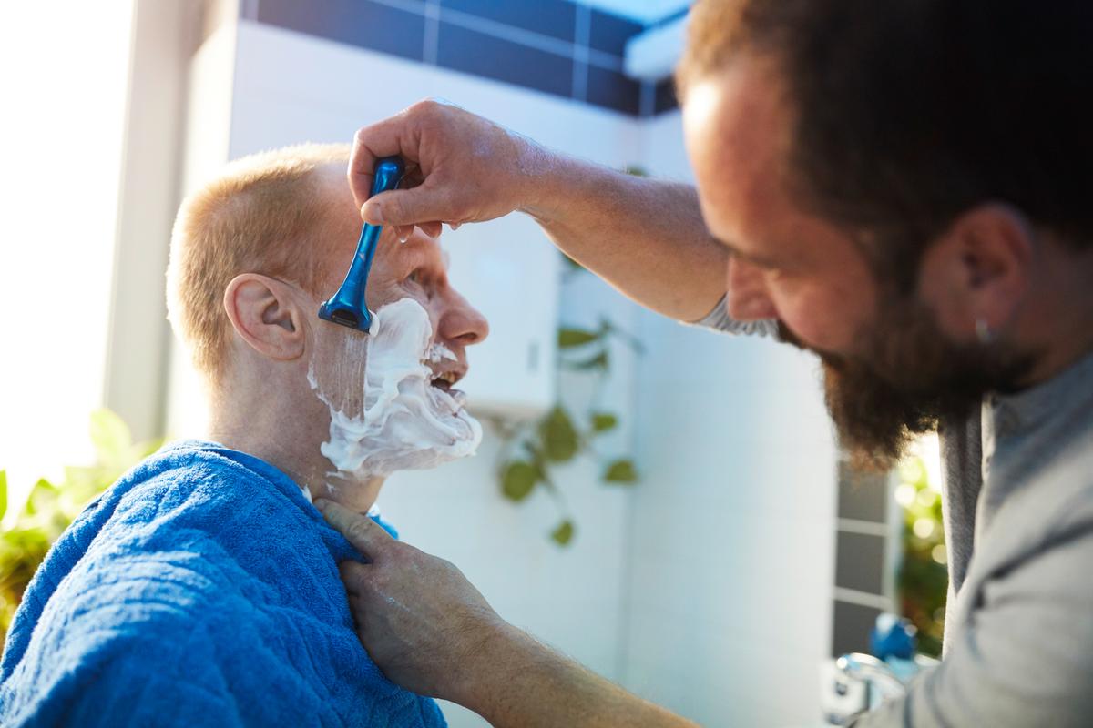 Auf dem 13. Bild sieht man eine Assistenten, der einen Kunden rasiert.