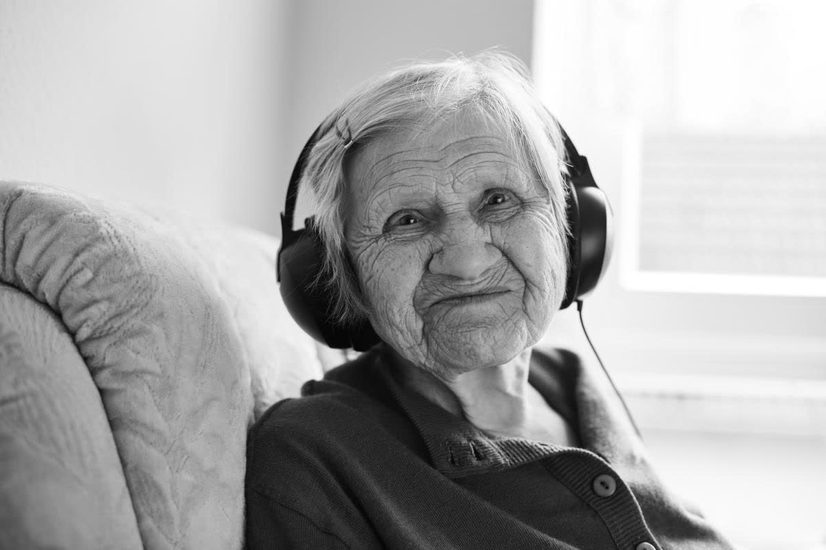 Auf dem 10. Bild sieht man eine ältere Frau, die mit Kopfhörer Musik hört.