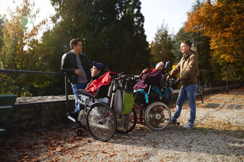 Auf dem 5. Bild sieht man eine kleine Gruppe Freiwilliger und Menschen im Rollstuhl bei einem Ausflug.